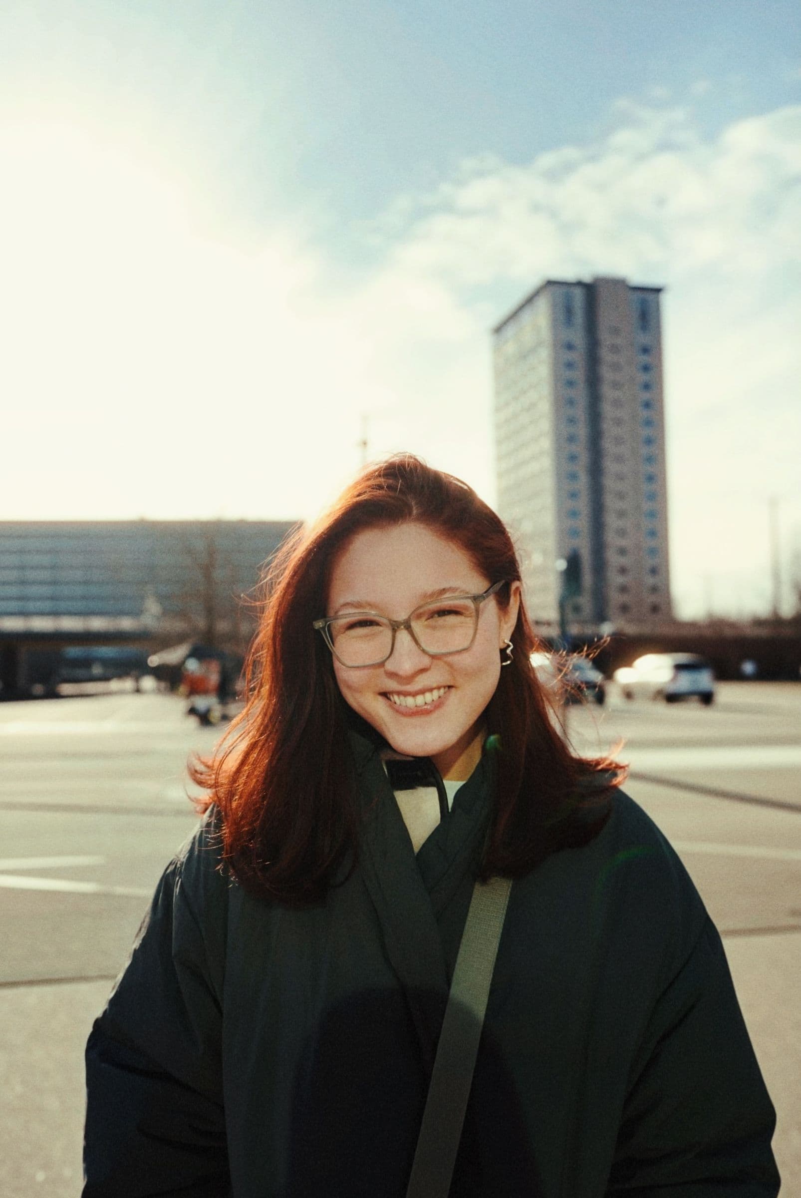 Kawsar smiling in the low sun in front of a tower block