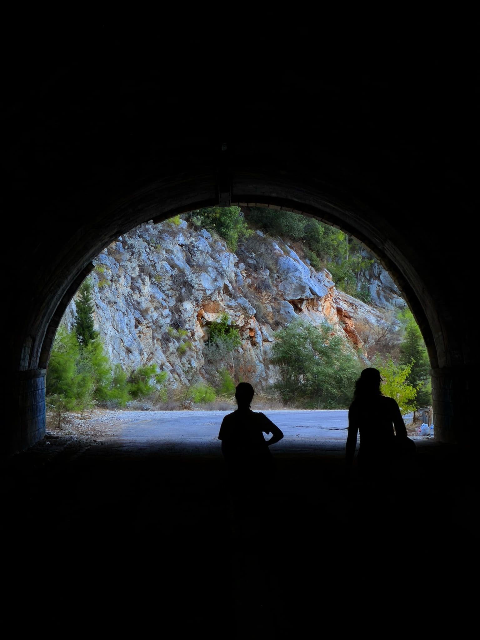 Two people silhouetted in a tunnel opening